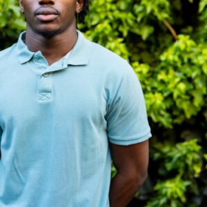 Midsection of african american man wearing pale blue polo shirt in garden, copy space