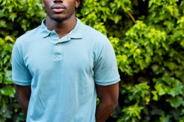 Midsection of african american man wearing pale blue polo shirt in garden, copy space